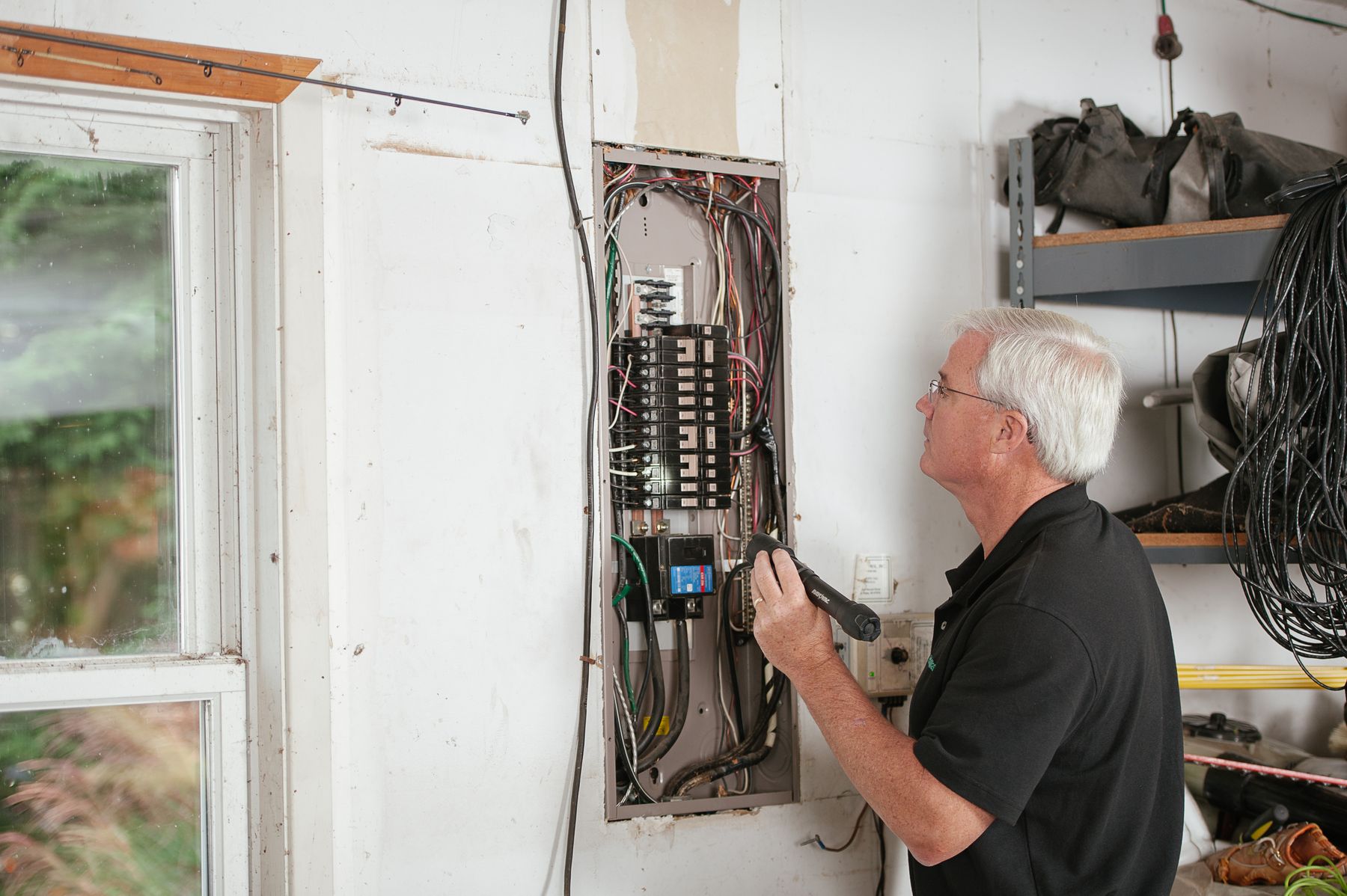 Électricien inspectant un tableau électrique pour diagnostiquer la cause d'une disjonction répétée